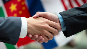 Two individuals shaking hands in a professional setting, with international flags in the background, symbolizing global partnerships and collaboration in IKN investment opportunities