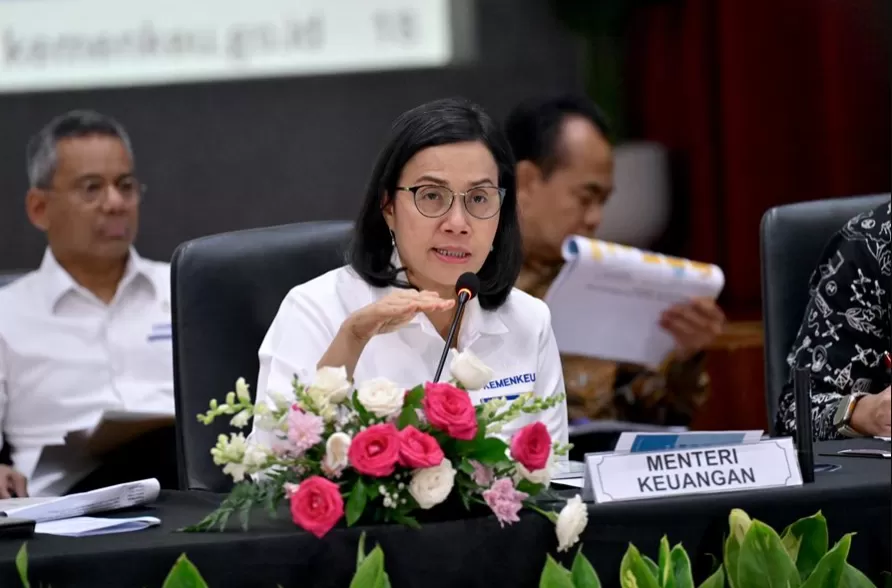 Finance Minister Sri Mulyani discusses Indonesia's Economic Stimulus during a press conference, sitting at a table with documents and flowers.