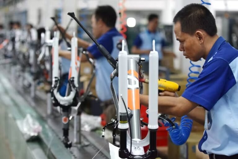 A worker assembling products in a factory, highlighting the challenges of deindustrialization in Indonesia's manufacturing sector.