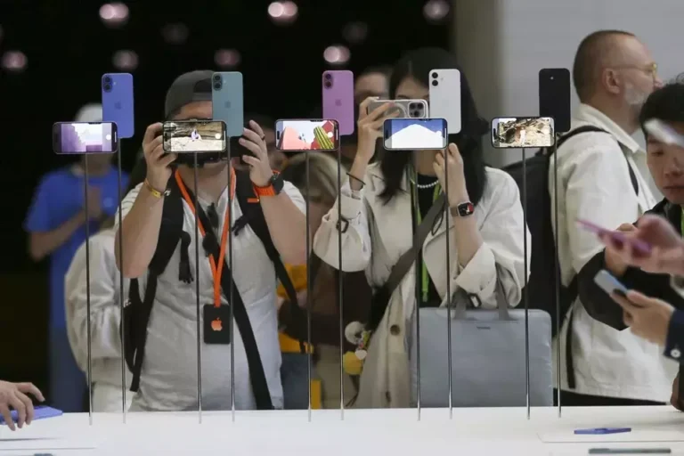 Visitors at an Apple event viewing and photographing the latest iPhone models, illustrating Apple Investment in Indonesia.