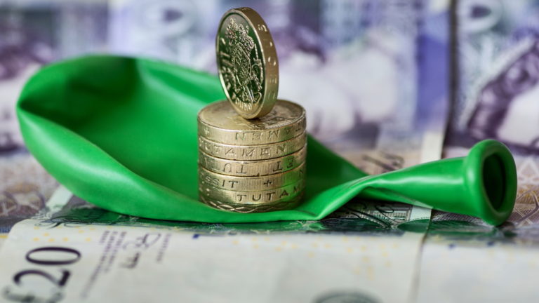 A stack of coins resting on a green balloon, symbolizing economic concepts, with Indonesian currency in the background, representing Indonesia's January 2025 deflation.