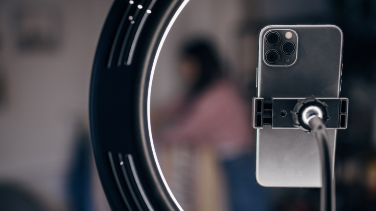A smartphone mounted on a ring light, often used by stock influencers to create engaging video content.