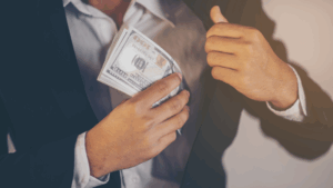 A man hiding US dollars in his suit jacket, illustrating how financial crimes can impact foreign investor confidence.