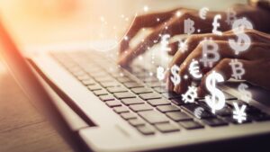 Hands typing on a laptop keyboard with digital currency symbols overlay, representing Indonesia digital economy investment.