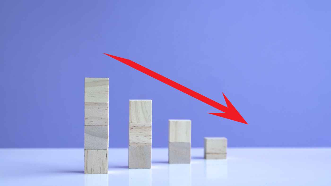 A downward red arrow over decreasing wooden block stacks symbolizing Indonesia tax revenue shortfall in 2025.
