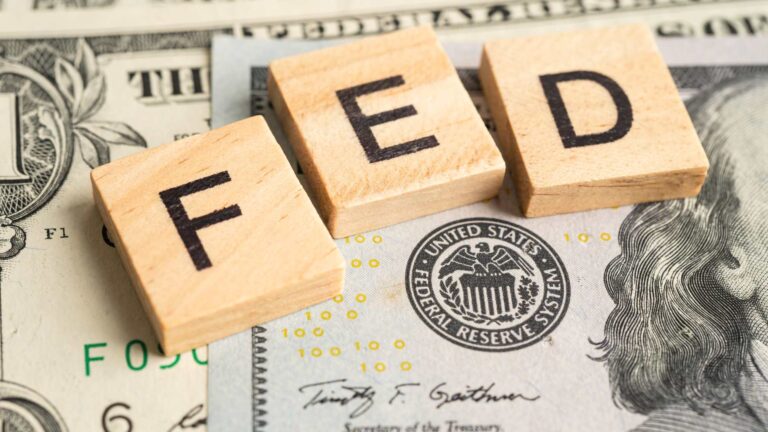 Wooden letter blocks spelling “FED” placed on U.S. dollar bills, symbolizing Trump Fed replacement plan and monetary policy.