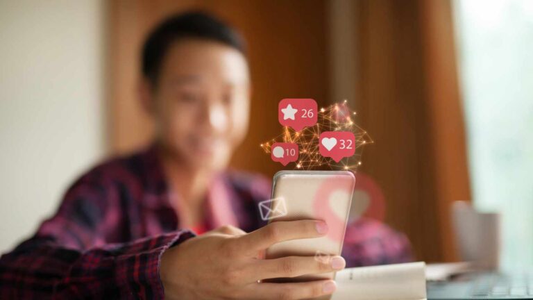 A young content creator uses a smartphone with social media notifications appearing above the screen, illustrating the concept of a social media tax.