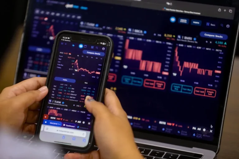 A person monitoring Indonesia stock exchange from his phone and laptop