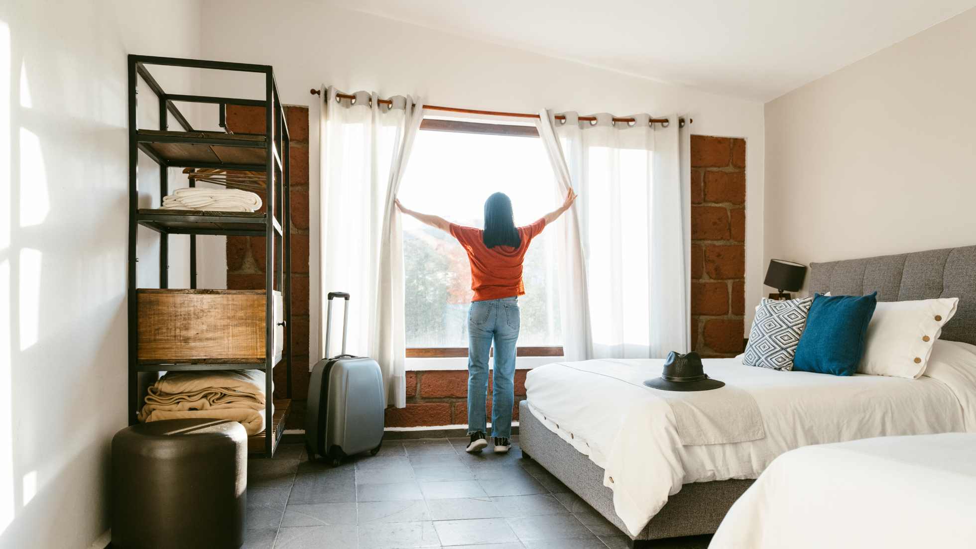 A guest opens hotel room curtains with sunlight streaming in, reflecting growth and innovation in the Indonesia hotel industry.