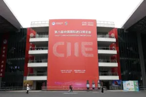 A large red entrance banner for the 8th China International Import Expo at the NECC Shanghai, highlighting the CIIE 2025 trade as visitors walk across the plaza.