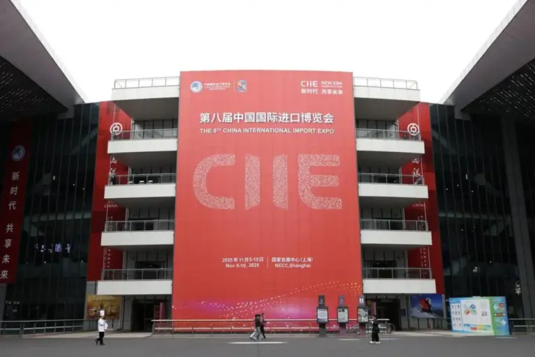 A large red entrance banner for the 8th China International Import Expo at the NECC Shanghai, highlighting the CIIE 2025 trade as visitors walk across the plaza.