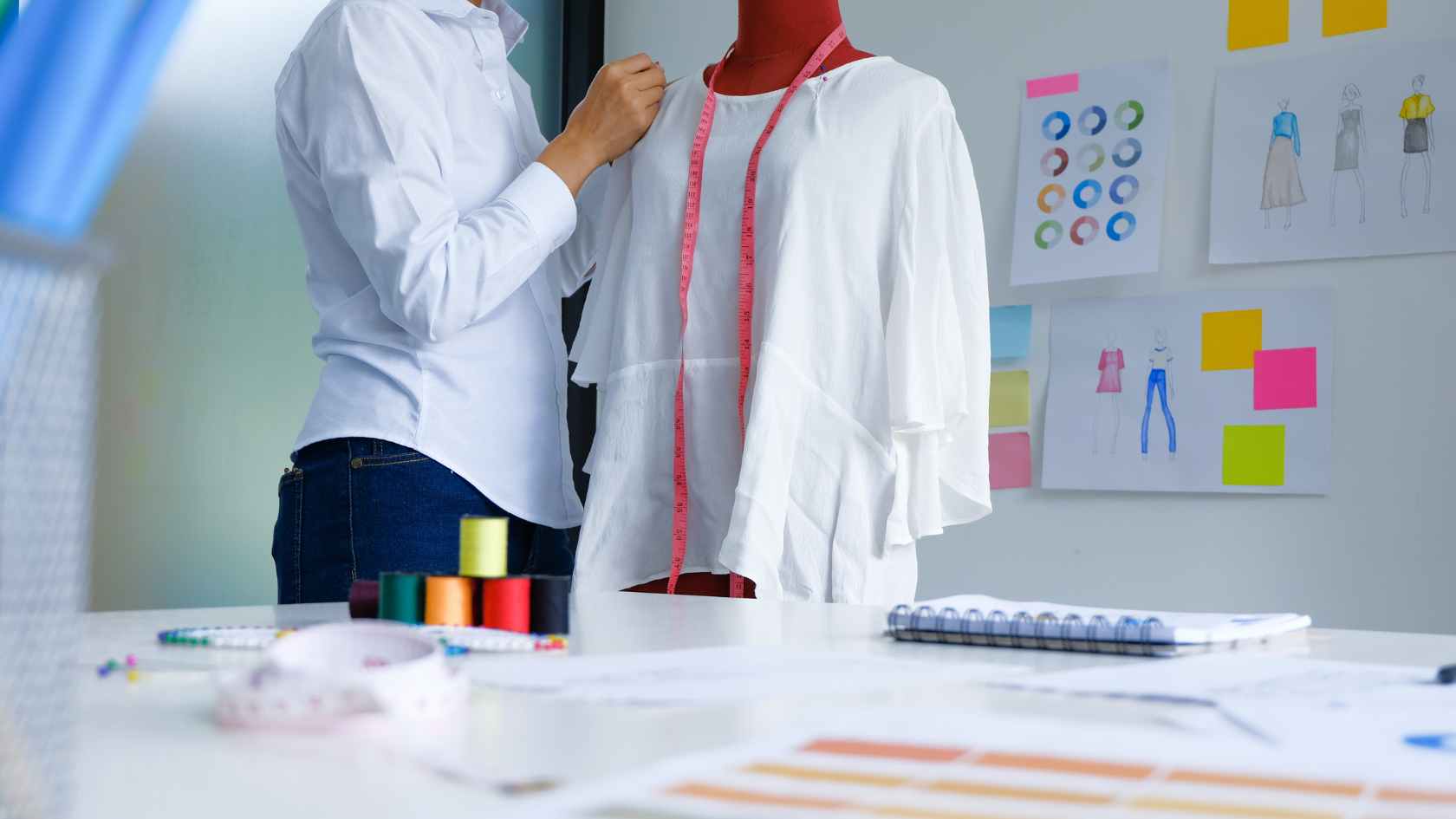 A designer adjusts a white modest outfit on a mannequin in a studio, showcasing creativity in the Indonesia modest fashion industry.