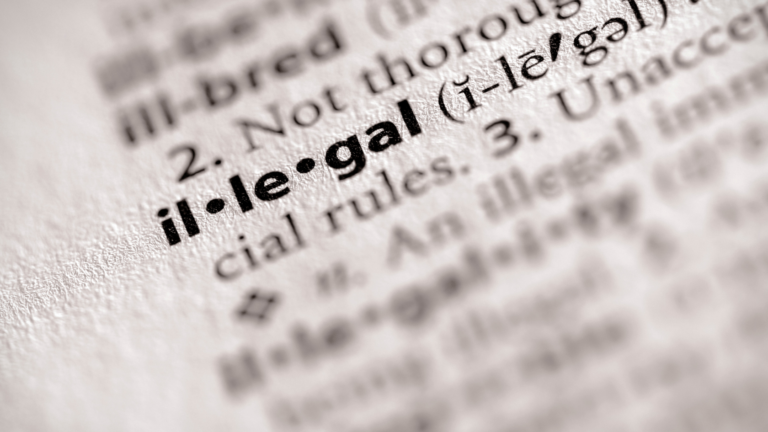 Illegal foreign workers highlighted in a close-up image of the word ilegal in a dictionary, symbolizing labor violations and compliance issues in Indonesia.