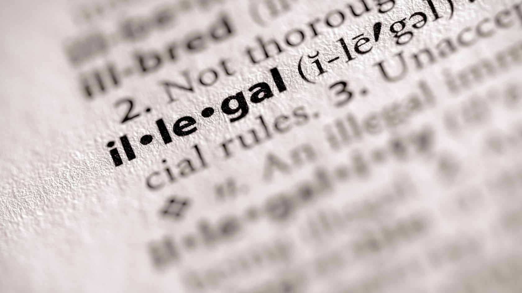 Illegal foreign workers highlighted in a close-up image of the word ilegal in a dictionary, symbolizing labor violations and compliance issues in Indonesia.